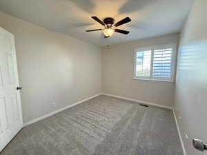 Empty room with carpet floors and a ceiling fan