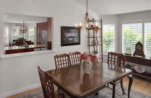 Dining area featuring a chandelier, wood finished floors, lofted ceiling, and baseboards