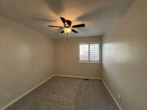 Unfurnished room with dark carpet, a textured ceiling, and ceiling fan
