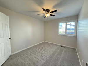 Spare room featuring light carpet and ceiling fan