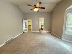 Unfurnished bedroom with a walk in closet, lofted ceiling, carpet flooring, and ceiling fan