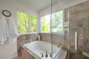 Full bath with a jetted tub, a tile shower, and baseboards