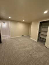 Finished basement with light carpet and recessed lighting