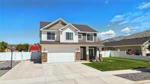 Craftsman-style house featuring stone siding, concrete driveway, an attached garage, board and batten siding, and a gate