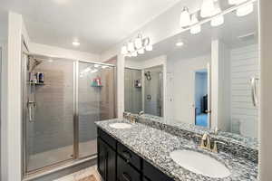 Full bath with a stall shower, double vanity, and recessed lighting