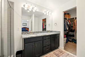 Bathroom featuring double vanity, a walk in closet, and a tile shower