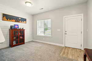 Carpeted foyer with baseboards and wood walls