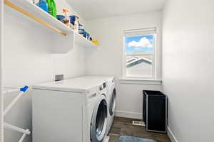 Laundry room with washing machine and clothes dryer, dark wood-type flooring, and baseboards