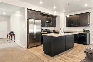 Kitchen featuring stainless steel appliances, a sink, light stone countertops, baseboards, and recessed lighting