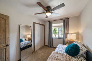 Carpeted bedroom with a ceiling fan, a closet, and a textured ceiling