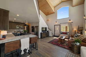 Living room featuring stairway, dark wood-type flooring, high vaulted ceiling, and recessed lighting