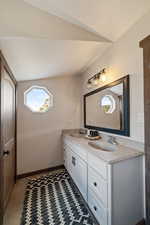 Bathroom featuring double vanity, vaulted ceiling, and a textured ceiling