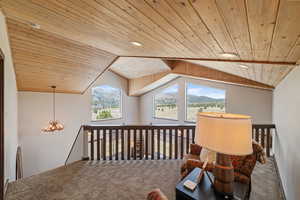 Bonus room with wood ceiling, carpet flooring, a chandelier, lofted ceiling, and a mountain view