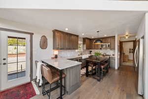 Kitchen with appliances with stainless steel finishes, a peninsula, backsplash, light wood-style flooring, and plenty of natural light
