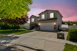 View of front of home featuring an attached garage, driveway, and stone siding