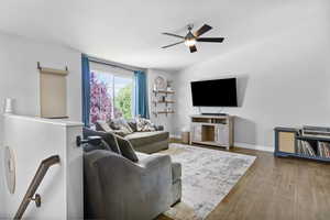 Living area with a ceiling fan, wood finished floors, and baseboards