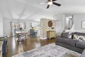 Living room with a ceiling fan, vaulted ceiling, dark wood-style flooring, and baseboards
