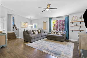 Living area featuring a ceiling fan, dark wood-style flooring, a chandelier, and plenty of natural light