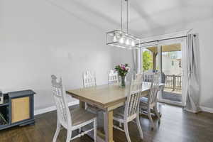 Dining area with baseboards, dark wood-type flooring, and a chandelier