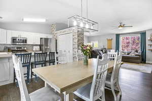 Dining area with vaulted ceiling, a ceiling fan, and dark wood-style floors