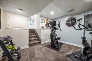 Exercise area with baseboards and a textured ceiling