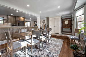 Dining area featuring crown molding, plenty of natural light, dark wood-type flooring, recessed lighting, and stairway