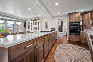Kitchen with light countertops, recessed lighting, brown cabinets, dark wood finished floors, and a peninsula