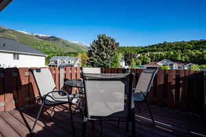 Deck with outdoor dining space, a mountain view, and fence