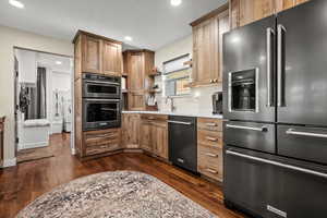 Kitchen featuring stainless steel appliances, dark wood finished floors, recessed lighting, light countertops, and brown cabinets