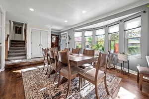 Dining space featuring crown molding, baseboards, wood finished floors, stairs, and recessed lighting