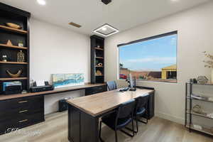 Office area with light wood-type flooring, built in desk, and recessed lighting