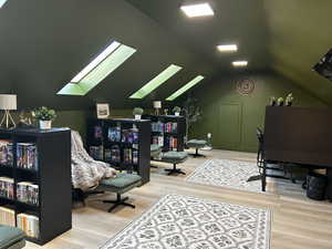 Office area with a skylight, wood finished floors, and vaulted ceiling
