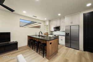 Kitchen with appliances with stainless steel finishes, a sink, a breakfast bar area, a peninsula, and dark countertops