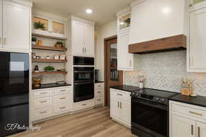 Kitchen with electric stove, custom range hood, built in microwave, tasteful backsplash, and open shelves