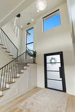 Entryway with light wood-style floors, a high ceiling, a chandelier, stairs, and recessed lighting