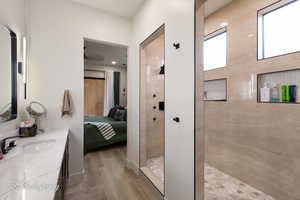 Bathroom with ensuite bathroom, wood finished floors, a walk in shower, and vanity