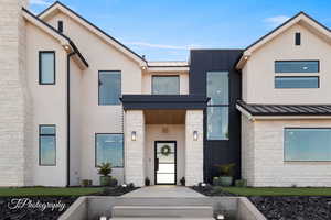View of front of property featuring a standing seam roof, metal roof, and stucco siding