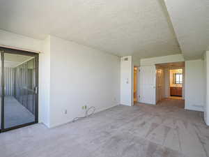 Primary bedroom with light carpet, a textured ceiling, and baseboards