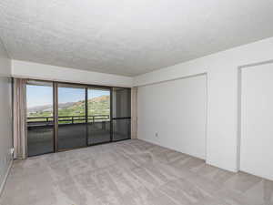 Living room with light carpet, a textured ceiling, and baseboards & balcony