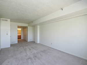 room featuring a textured ceiling, light carpet, and baseboards