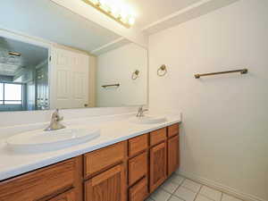 Full bath with tile patterned flooring, double vanity, and baseboards
