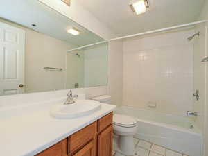 Full bath with toilet, tile patterned floors, vanity, shower / tub combination, and a textured ceiling