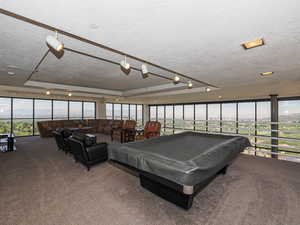 Sky Room Game room featuring a textured ceiling, carpet flooring, pool table, and a wall of windows