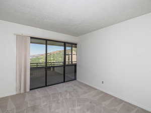 Carpeted empty room with a textured ceiling and baseboards