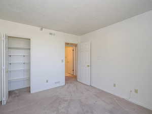 2nd bedroom with carpet flooring, a textured ceiling, baseboards, and a closet