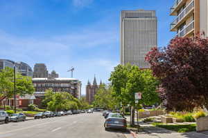 View of asphalt street featuring sidewalks, a city view, curbs, and street lighting