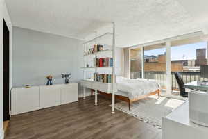 Bedroom featuring wood finished floors, access to exterior, and a textured ceiling
