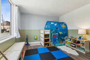 Workout area featuring wood finished floors, a textured ceiling, and baseboards