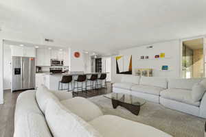 Living room with dark wood-style flooring, a textured ceiling, and recessed lighting