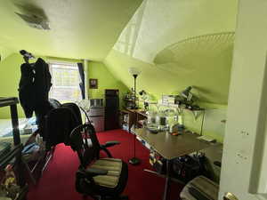 Carpeted office featuring lofted ceiling